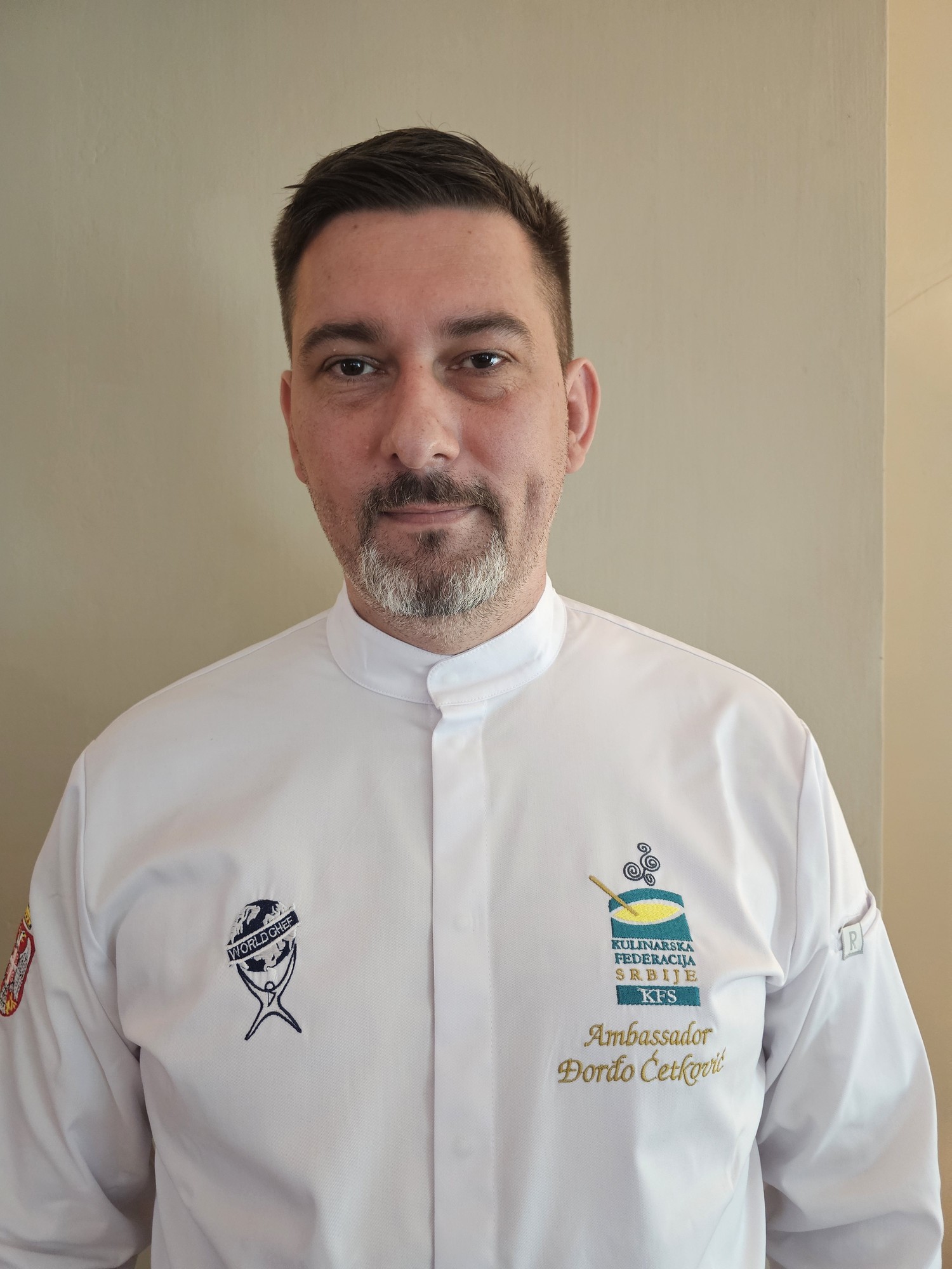 Djordjo_Cetkovic, Executive Chef at Pano Kato Grill, Pizza & Deli, in a chef's jacket embroidered with the Culinary Federation of Serbia (KFS) emblem and Ambassador ?or?o ?etkovi?.
